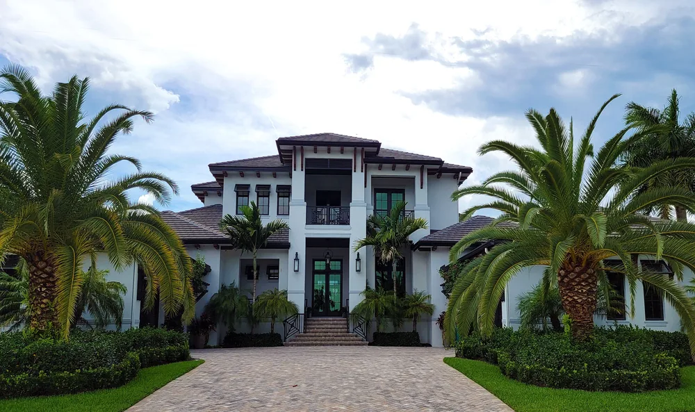 A modern home with palms and a paved forecourt