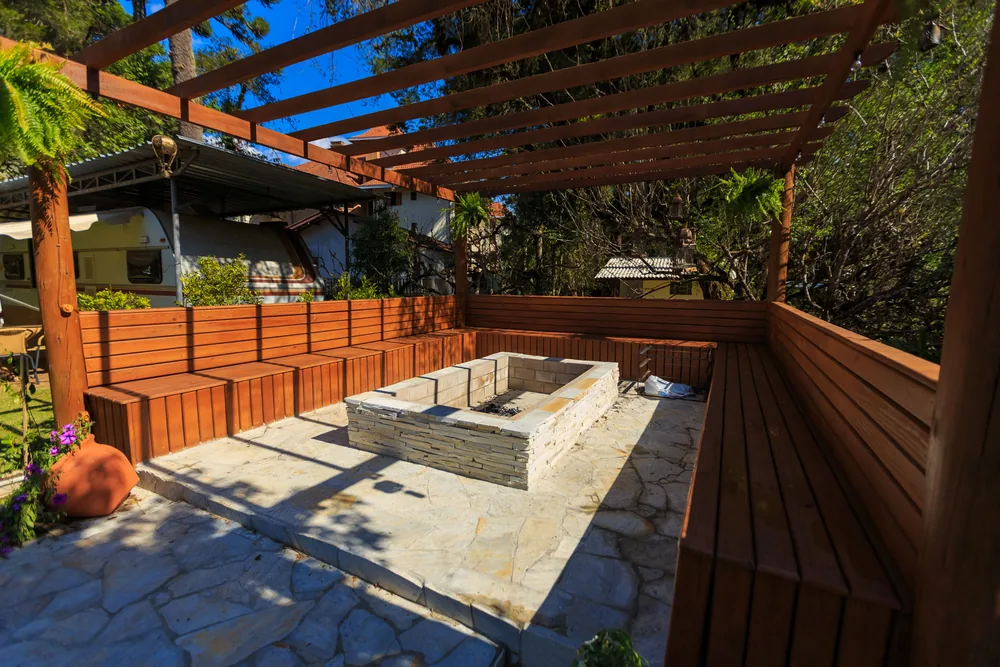 A patio with a stone fire pit and bench seating