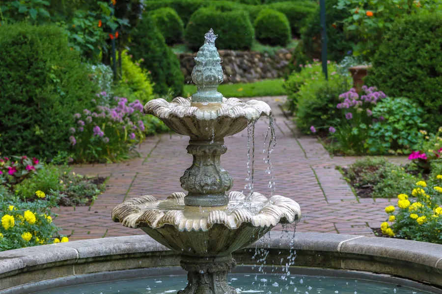 A stone fountain in a planted garden
